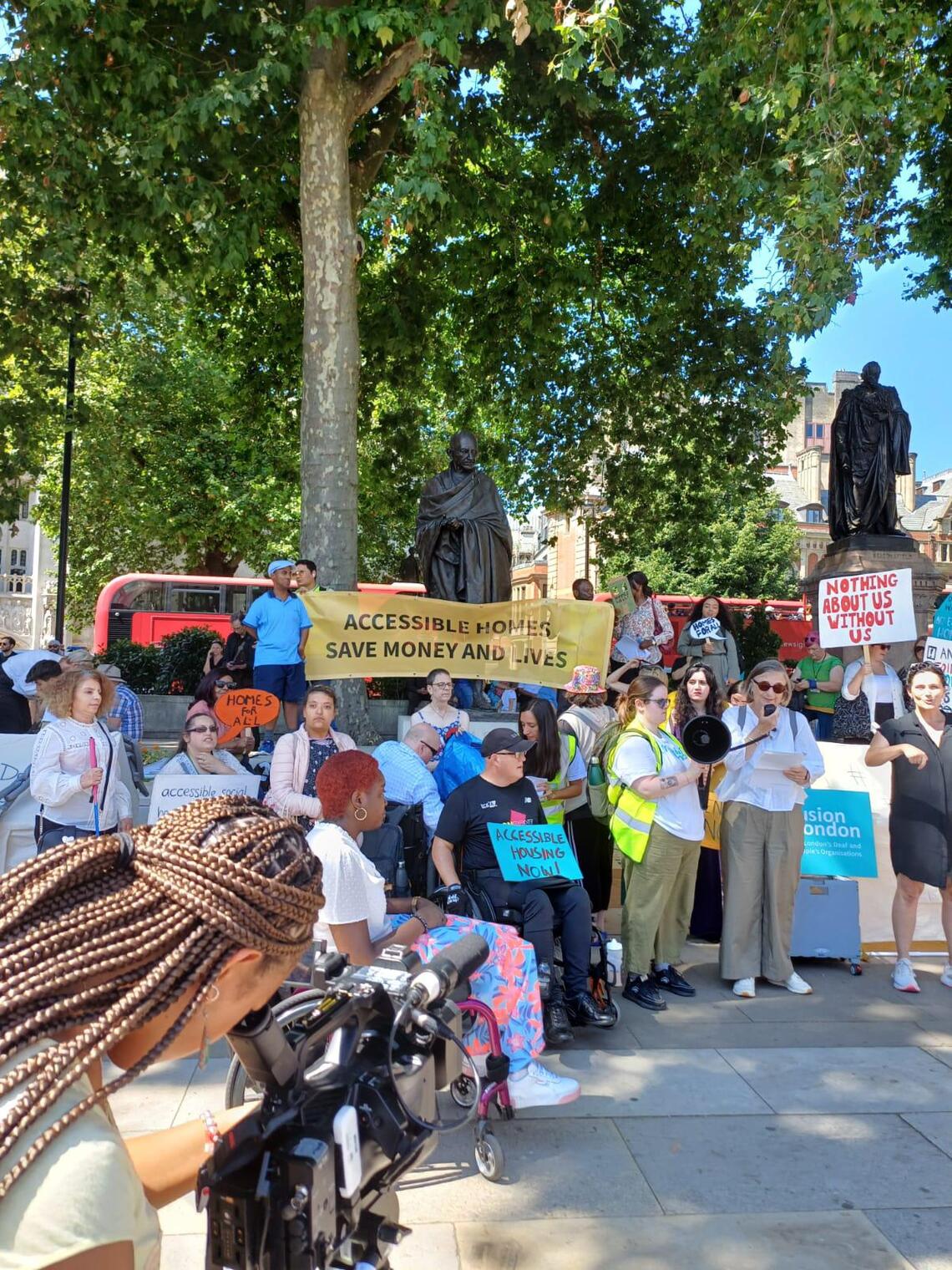 A group of Disabled people and campaigners standing in from of a tree at Westminster campaigning for accessible housing in London